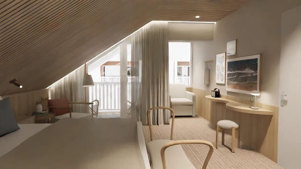 Helles Hotelzimmer im Dachgeschoss mit markanten Holzlamellen an der Schräge, einem kleinen geschwungenen Schreibtisch und Zugang zum sonnigen Balkon.